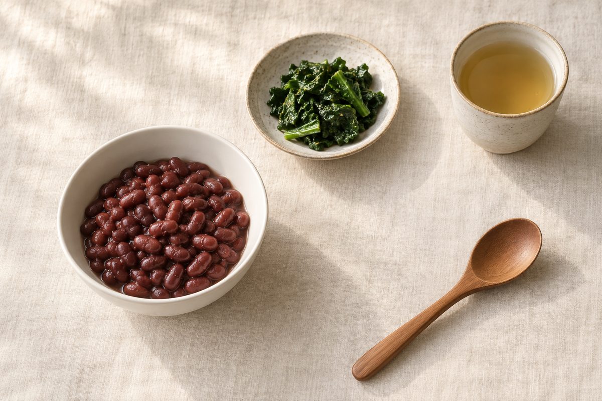 A bowl of red beans, a dish of dark greens and a cup of tea